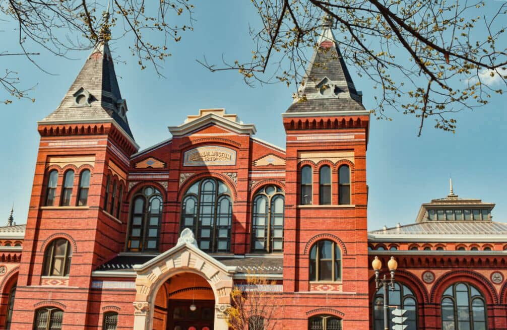 Red brick historic building with twin towers and arched entrance against a clear blue sky, perfect for a 48-Hour Family Vacation in DC.