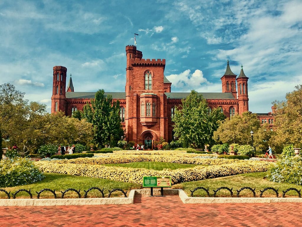 A view of a historic brick building with towers surrounded by lush gardens under a partly cloudy sky is featured in the Family-Friendly Guide to the Smithsonian.