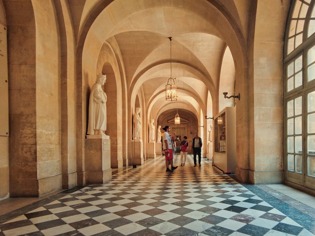 People walking down a hallway in a building with arches.