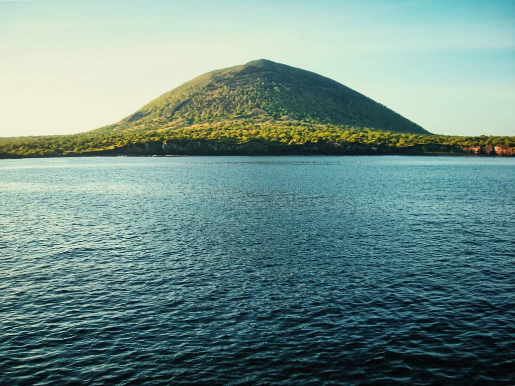 A mountain in the middle of a body of water.