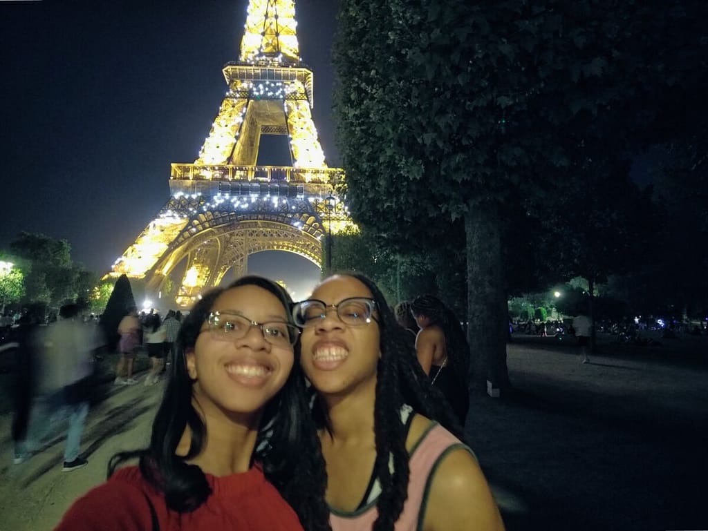 Two women posing in front of the eiffel tower.