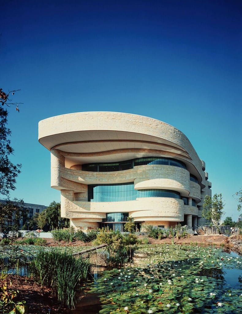 Modern, curved building with a family-friendly, layered design surrounded by a pond with lily pads.